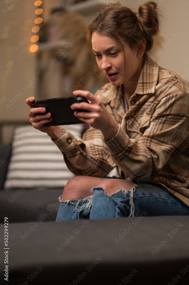 Video games on a portable game console. Girl gamer holds a game console in her hands. Fun pastime, video games, joystick, chat online with friends, tournaments, competitions, win, prizes. Video games on a portable game console. Girl gamer holds a game console in her hands. Fun pastime, video games, joystick, chat online with friends, tournaments, competitions, win, prizes.