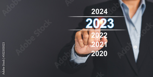 Businessman pointing to digital 2023 calendar. Countdown to 2023 concept. New Year's Eve and changing the year 2022 to 2023