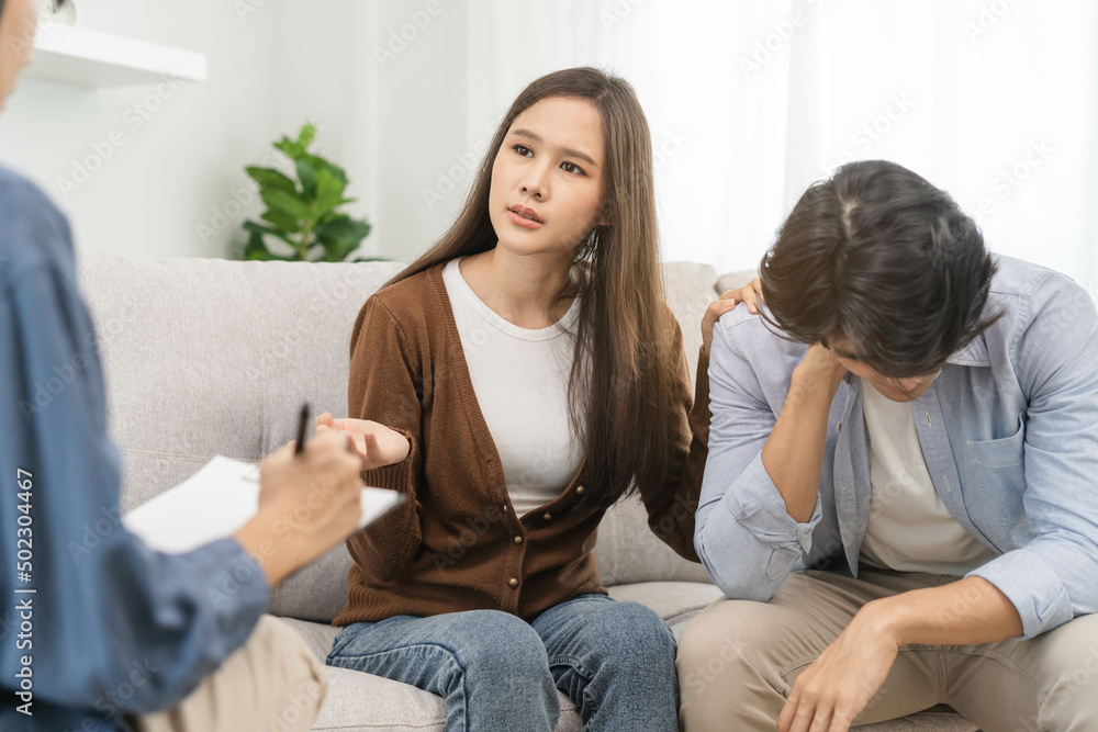 Psychology, depression asian young couple love, woman, man patient consulting problem mental health with psychologist, psychiatrist at clinic together, wife encouraging husband, therapy health care. Psychology, depression asian young couple love, woman, man patient consulting problem mental health with psychologist, psychiatrist at clinic together, wife encouraging husband, therapy health care.