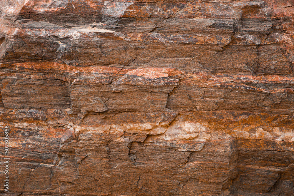 An image of a real orange and red  grunge rock wall texture with chips, cracks, and scrapes. 