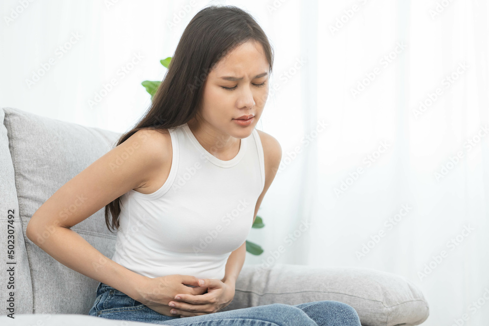 Flatulence asian young woman, girl hand in stomach ache, suffer from food poisoning, abdominal pain and colon problem, gastritis or diarrhoea. Patient belly, abdomen or inflammation, concept. Flatulence asian young woman, girl hand in stomach ache, suffer from food poisoning, abdominal pain and colon problem, gastritis or diarrhoea. Patient belly, abdomen or inflammation, concept.