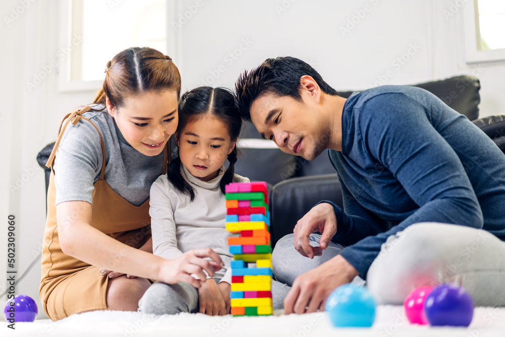 Portrait of enjoy happy love asian family father and mother with little asian girl smiling activity learn and skill brain training play with toy build wooden blocks board education game at home