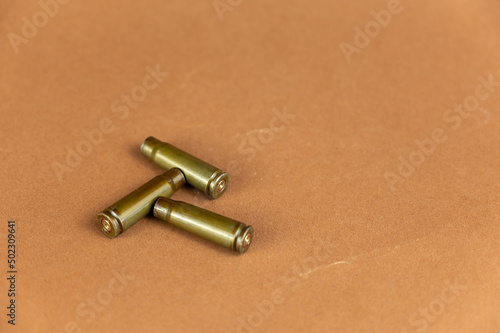 Empty casings against a brown background. Three automatic rifle casings.