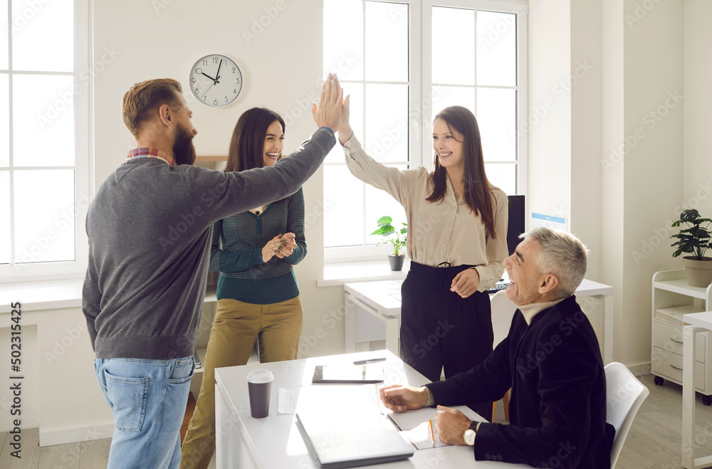 Obraz premium Overjoyed businesspeople give high five celebrate shared business success or goal achievement in office. Smiling colleagues or coworkers engaged in teambuilding activity at work. Teamwork concept.