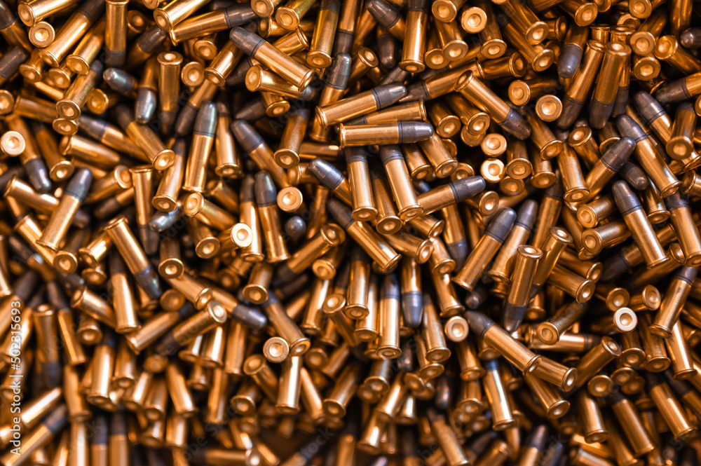 Heap of black and golden small-caliber bullets on table Heap of black and golden small-caliber bullets on table