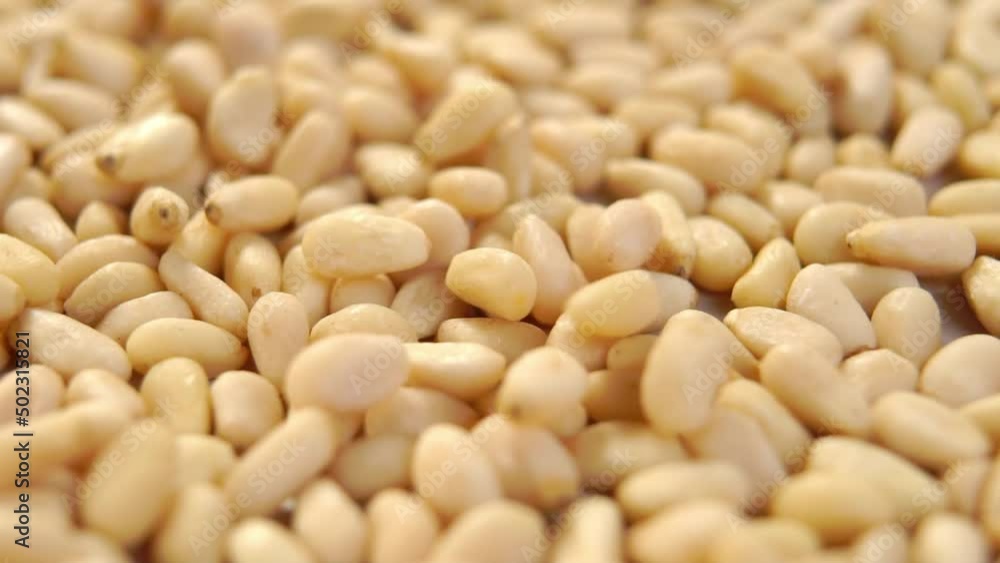 Whole peeled siberian pine nuts. Raw hulled cedar seeds falling in slow motion. Shelled kernels. Macro. Rotation Whole peeled siberian pine nuts. Raw hulled cedar seeds falling in slow motion. Shelled kernels. Macro. Rotation