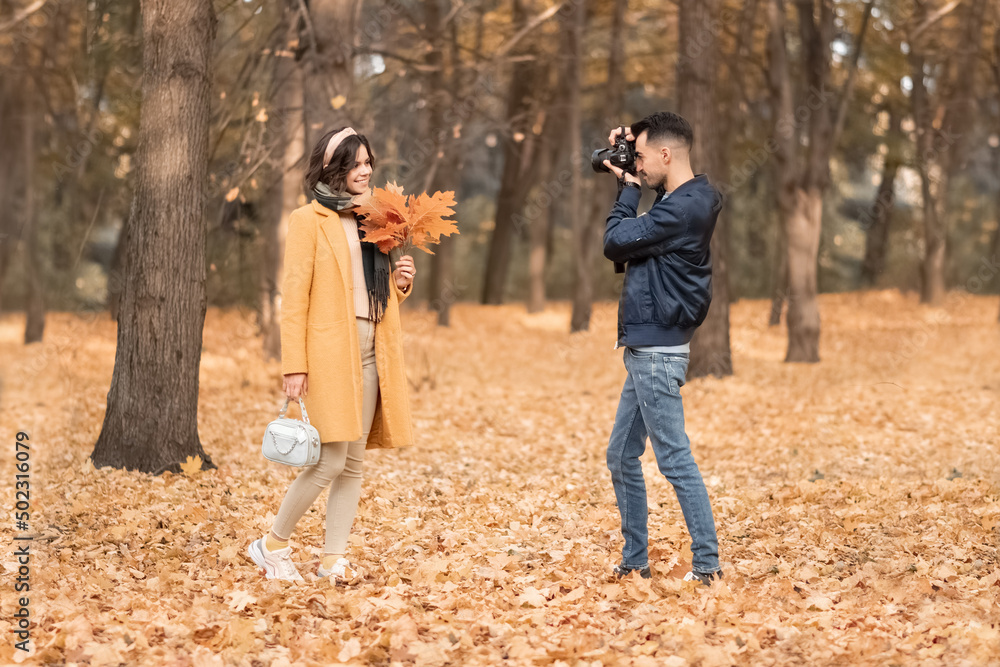 .the guy photographs the girl in the autumn forest