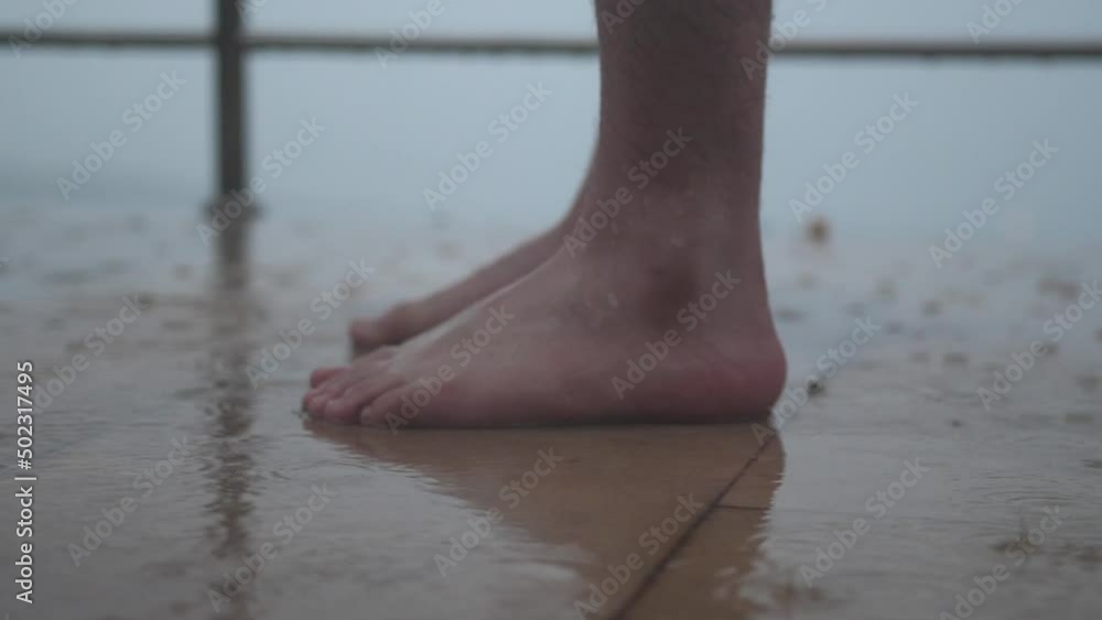 During raining activity, close up barefoot slowly stomping in water puddles and stand, tropical rainy season, climate changes During raining activity, close up barefoot slowly stomping in water puddles and stand, tropical rainy season, climate changes