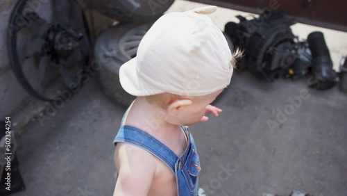 baby mechanic looks at camera then bends down for the ball closeup