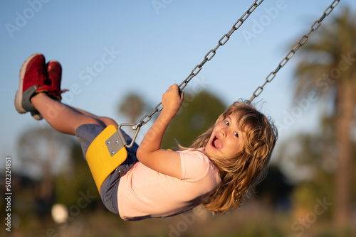 Child boy playing at kids playground. Active little child on playground. Kids play on school or kindergarten yard. Active kid on colorful swing. Little boy swinging.