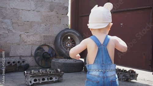 baby mechanic waving his arms against backdrop of auto parts slowmotion