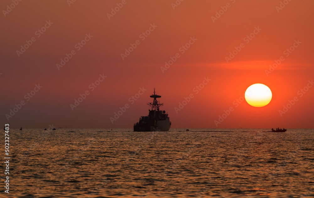 Silhouette military war ship and the sun.