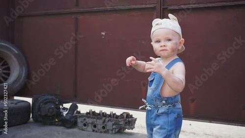 serious kid mechanic stands and looks at camera