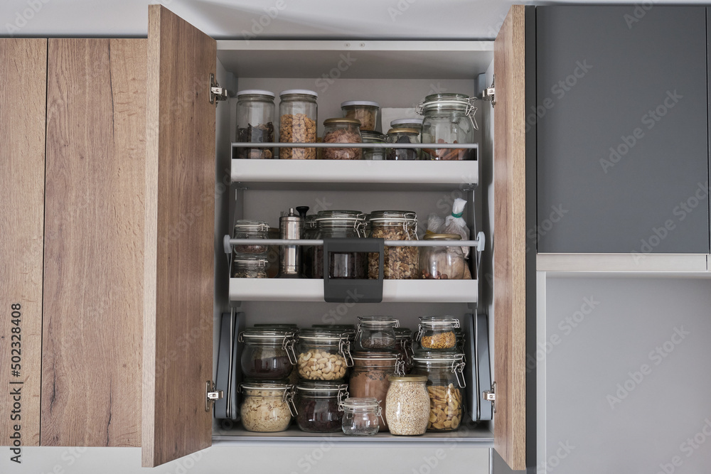 Variety of dry foods, grains, nuts, cereals in glass jars in kitchen cupboard. Zero waste storage concept. Variety of dry foods, grains, nuts, cereals in glass jars in kitchen cupboard. Zero waste storage concept.