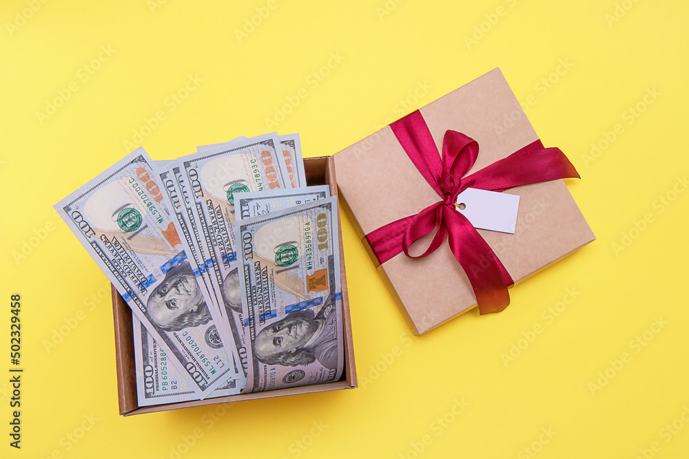 gift box filled with money, next to it is a lid tied with a satin ribbon and with an empty tag gift box filled with money, next to it is a lid tied with a satin ribbon and with an empty tag