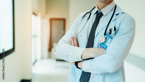 Closeup of Mature Male Doctor Wearing white Coat Standing in Hospital Corridor. Concept Of Medical Technology and Healthcare Business.