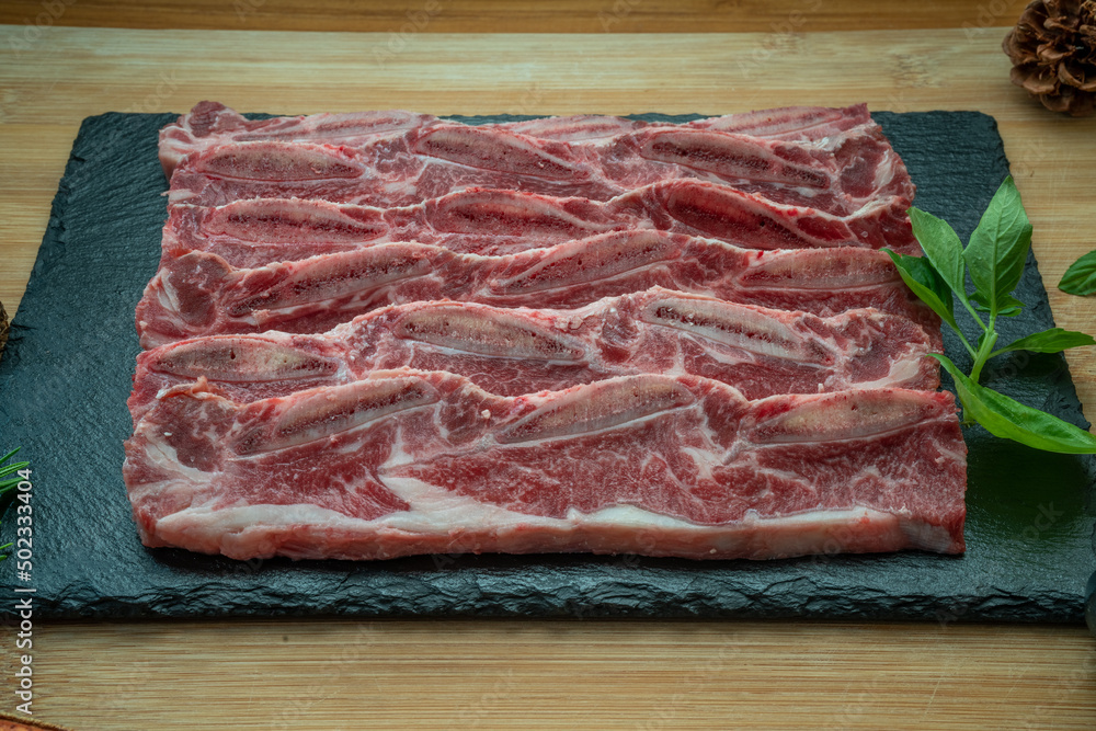 Beef Short Ribs (Sliced) Bone-in on wooden background.Cross Cut Short Ribs beef on black plate. Beef Short Ribs (Sliced) Bone-in on wooden background.Cross Cut Short Ribs beef on black plate.