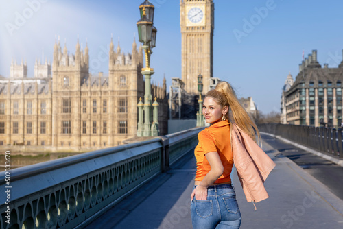 A blonde tourist woman walks over the Westminster Bridge in London, England, during her sightseeing trip