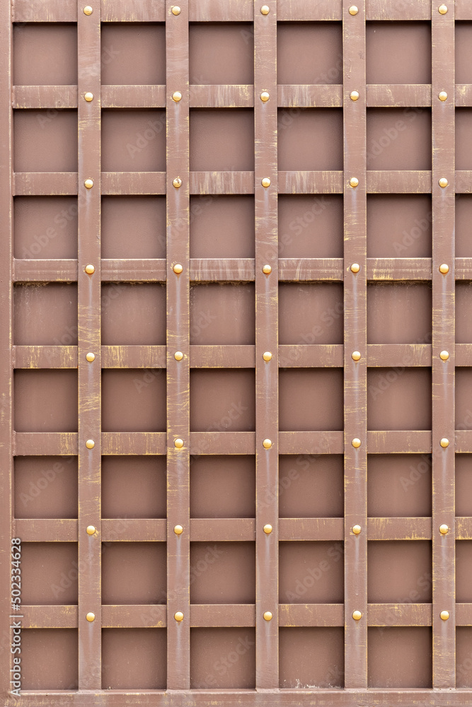 Metal cage on a brown background, old texture with a geometric pattern. Shabby metal gates.