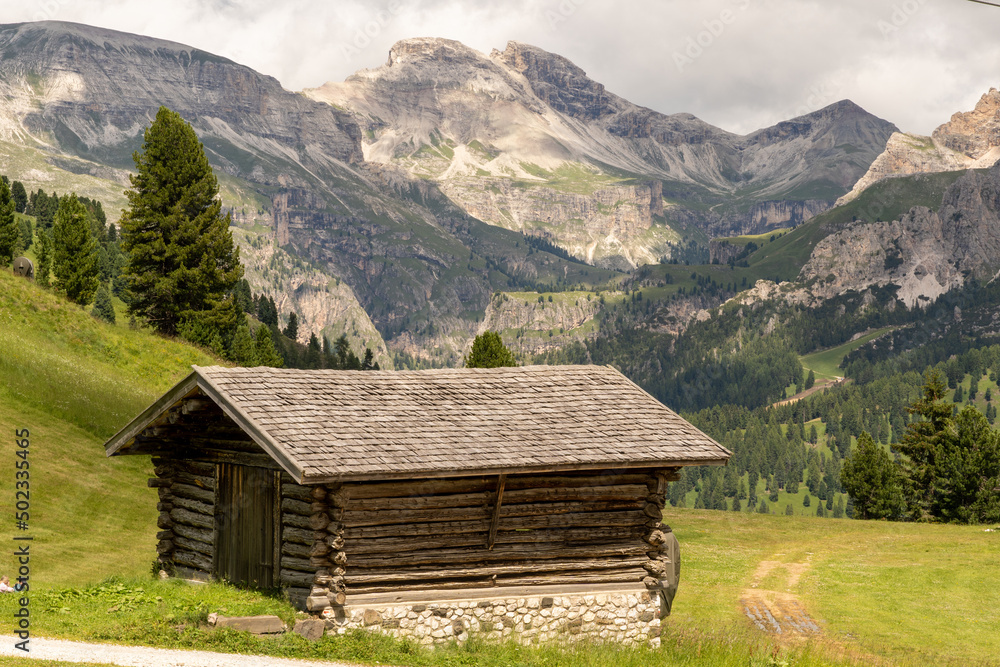 Small wooden cabin with mountains in the background in Val Gardena. South Tyrol