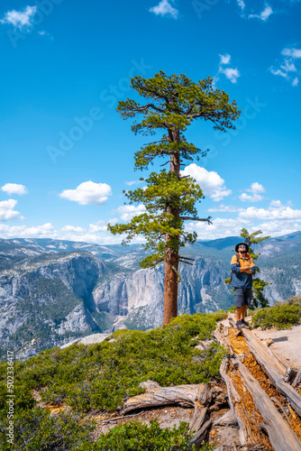A young man with a brown jacket in Sentinel Dome looking at Upper Yosemite Fall, Yosemite National Park. United States photo
