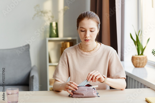 Tableau sur toile Minimal portrait of young woman putting birth control pills in cosmetic bag with