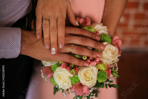 Touching hands of groom and bride near bouquet of flowers. Wedding day concept. Wedding picture. Love is.