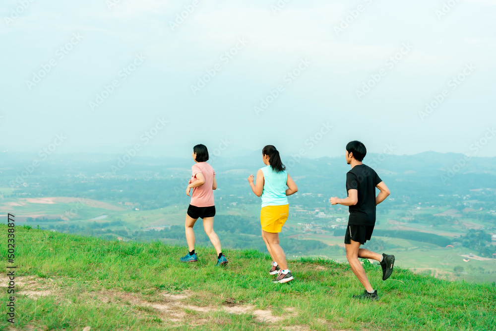 Asian man and woman trail runner running. On the high mountains, beautiful scenery. It's a trail running practice. on a bright day Behind is a beautiful mountain view.. Asian man and woman trail runner running. On the high mountains, beautiful scenery. It's a trail running practice. on a bright day Behind is a beautiful mountain view..