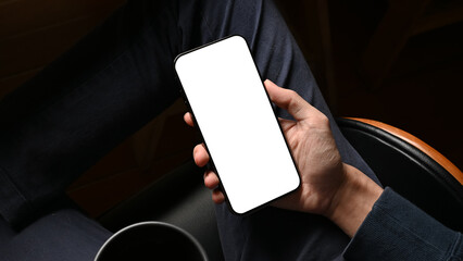 Businessman using his cellphone at his desk. Phone white screen mockup.