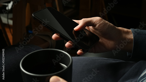 Close-up image, Hipster man sipping morning coffee while using his cellphone