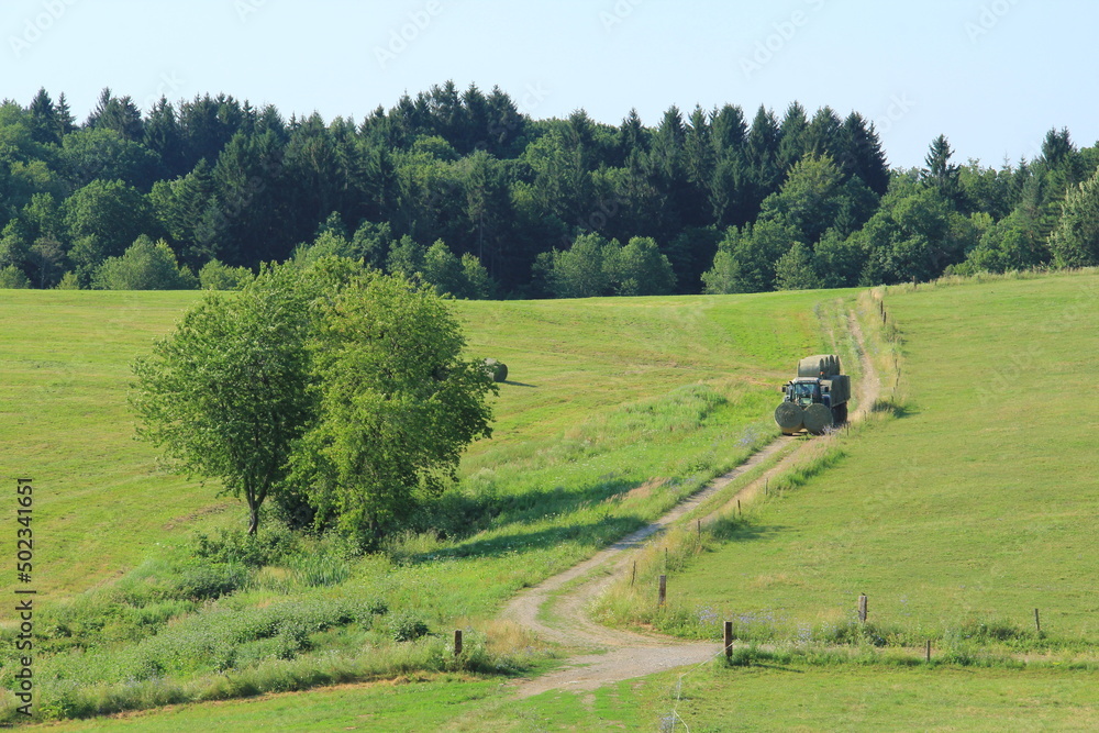 Tractor driving hay fresh bale on the field. Tractor driving hay fresh bale on the field.