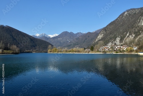 View of lake at Most na Soci and Modrej village with snow covered mountain peak of Julian alps behind in Severna Primorska, Slovenia