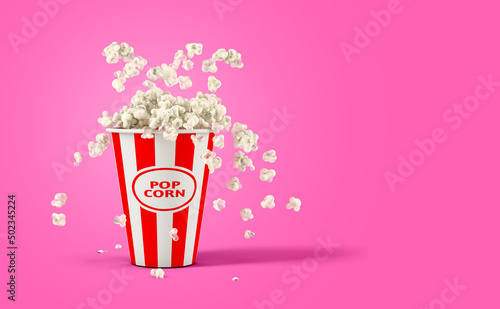Falling popcorn in box isolated on a pink background with copy space