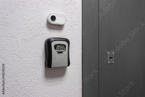 Key box with a combination lock next to the door and a bell button on the wall photo