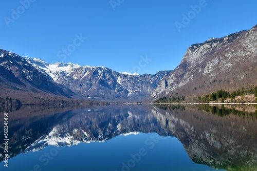 Snow covered mountain peaks in Julian alps and lake Bohinj with the reflection of the mountains in the lake in Gorenjska, Slovenia © kato08