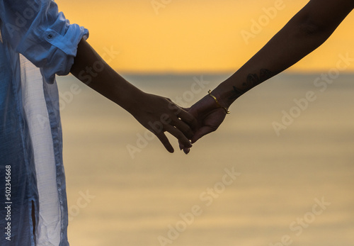 Girls are holding hands with ocean during sunset © Luk
