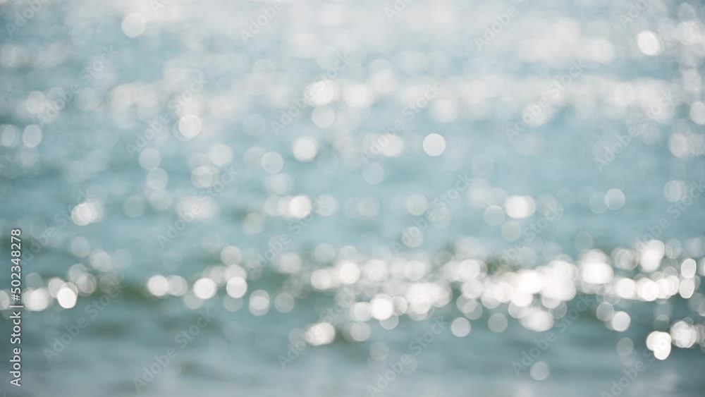 Beautiful glittering bokeh in natural sea ocean waves blurry background at day. The round colorful bokeh shine from sea wave lights. Relax lifestyle. Abstract concept.
