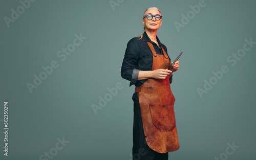 Cheerful jewellery maker holding a ring mandrel in a studio photo