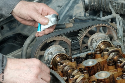 Car engine repair in a car service center. Applying a sealant when replacing the valve cover gasket. The cylinder head of the internal combustion engine.