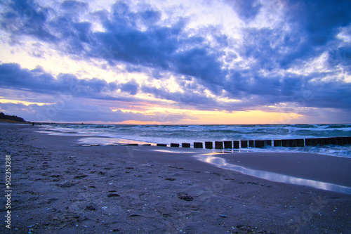 sunset on the beach of the Baltic Sea. Groynes reach into the sea. blue hour