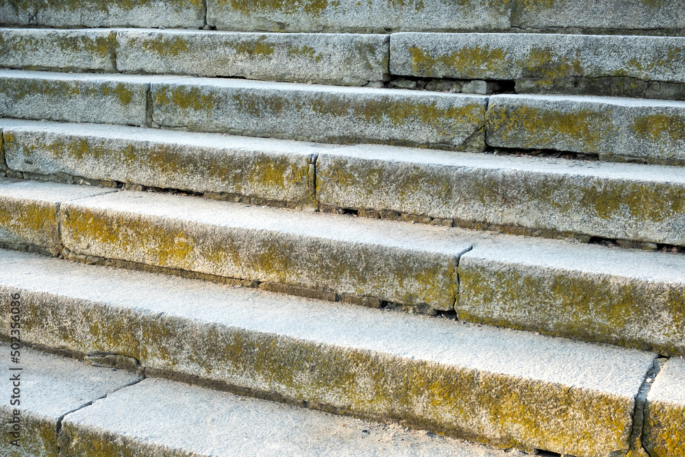 Close-up stone steps with moss texture. The edges and corners of the stone granite stairs. Concrete fragments of steps architecture. Beautiful grey stair steps. Close-up stone steps with moss texture. The edges and corners of the stone granite stairs. Concrete fragments of steps architecture. Beautiful grey stair steps.