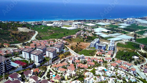 Top view of agricultural city by sea. Stock footage. Agricultural fields with greenhouses are located in city on coast of blue sea. Beautiful landscape of southern modern city with agriculture © Media Whale Stock