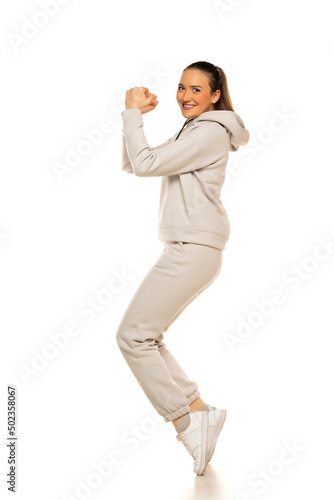 a young woman in a gray tracksuit poses against a white background in the studio