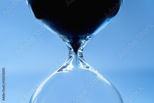 Sand moves through hourglass. Close up of hour glass clock. Hourglass as time passing concept for business deadline, urgency and running out of time.