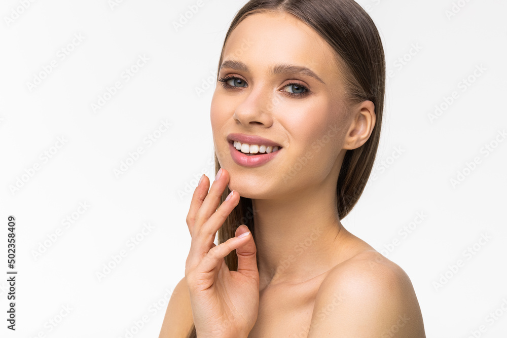 Portrait of beautiful girl smiling at camera, touching natural face without makeup, healthy glowing facial skin and white teeth, standing over white background Portrait of beautiful girl smiling at camera, touching natural face without makeup, healthy glowing facial skin and white teeth, standing over white background