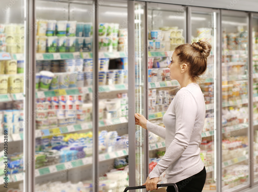 Woman choosing frozen food from a supermarket freezer. Woman choosing frozen food from a supermarket freezer.