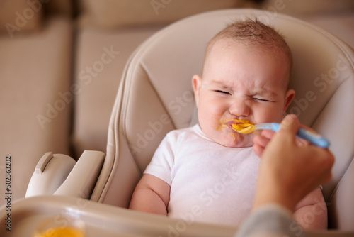 Baby making funny faces while refusing to eat porridge