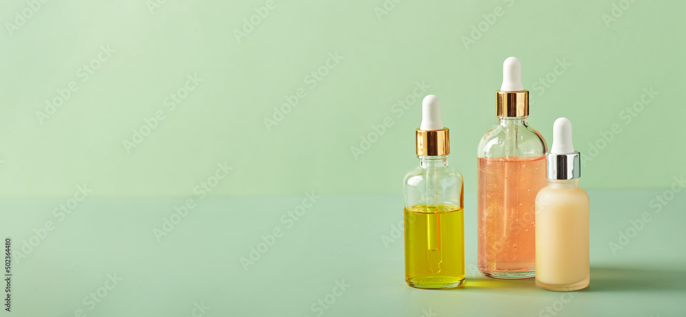 Cosmetic care products in glass bottles with orchid flowers - serums, cream, gel, oils. Concept for face and body care, wellness and spa, tropical relaxation.