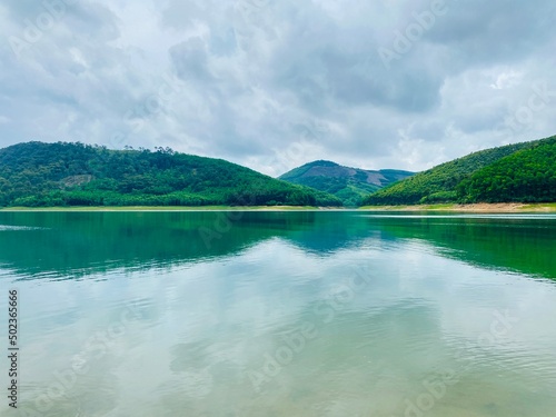Beautiful natural scenery on a cloudy summer morning with a blue lake and green mountains reflected on the lake surface