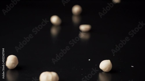 Hazelnuts fall on a black table, slow motion
